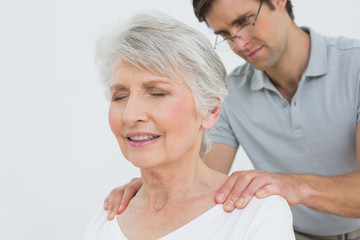 Fototapeta na wymiar Male physiotherapist massaging a senior womans neck