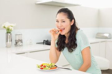 Young woman eating salad in the kitchen
