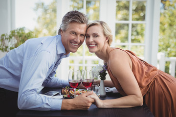 Portrait of romantic couple holding hands while having meal