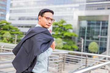 Asia young business man in front of the modern building in downtown .Concept of young  business people