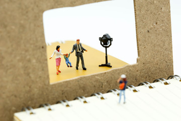 Miniature people : journalists , cameraman ,Videographer at work shooting  on  family, production concept.