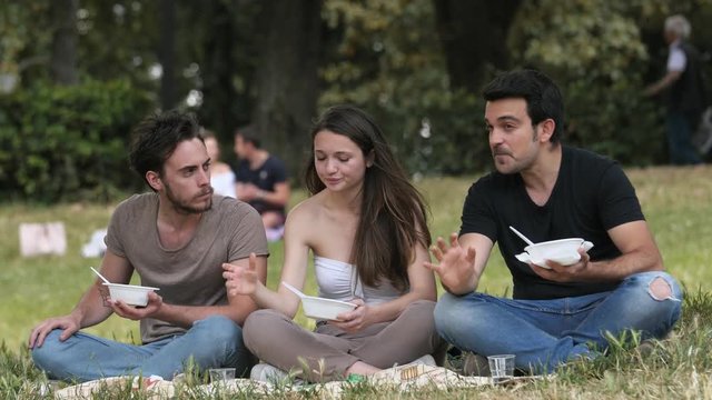 group of friends chatting and relaxing by having a picnic at the park