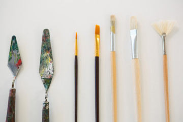 Palette knives and paint brushes arranged in a row