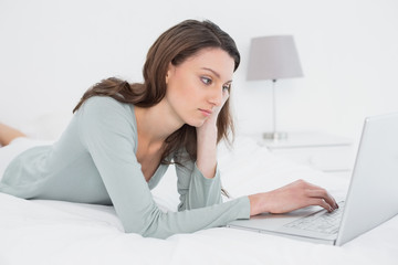 Relaxed casual young woman using laptop in bed