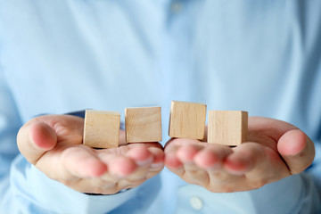 Hand holding four blank wooden cubes, business concept background, mock up, template