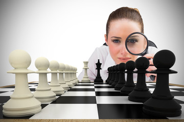 Composite image of thinking businesswoman with magnifying glass with chessboard