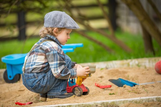 Small caucasian boy playing in sandpit