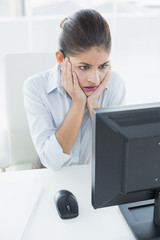Worried businesswoman looking at computer in office