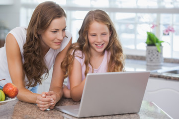 Girl and mother using laptop in house