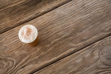 Coffee in disposable cup on wooden table