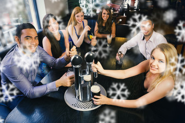 Young friends sitting together and pulling pints in a restaurant against snowflakes