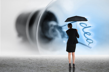 Young businesswoman holding umbrella against idea filament in light bulb