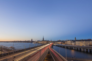 Motion blurred light tracks of highway traffic to Old city (Gamla Stan) cityscape pier architecture with historic town houses in Stockholm, Sweden. Creative long time exposure landscape photography