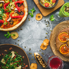 Vegetarian food - pizza, salad, pie and fruit drinks on dark background. Flat lay, top view. Food background