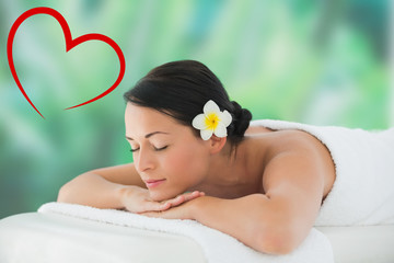 Obraz na płótnie Canvas Beautiful brunette relaxing on massage table against heart