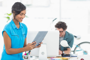  Smiling businesswoman using tablet with colleagues behind