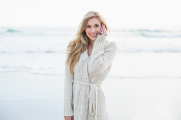 Cheerful blonde woman in wool cardigan making a phone call