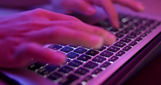 Typing on notebook computer keyboard with pink light