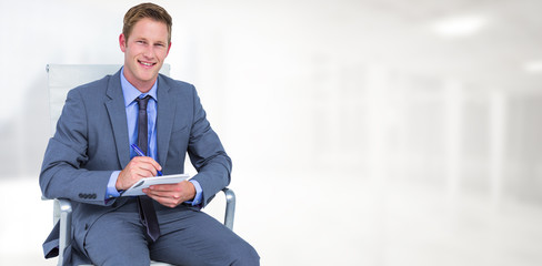 Businessman writing down on a notebook against modern room overlooking city