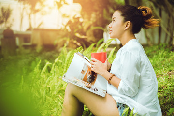 Asian woman Sitting relax. Read magazines and drink coffee. in the garden