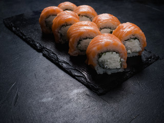 Philadelphia sushi rolls on dark background. Food photography art