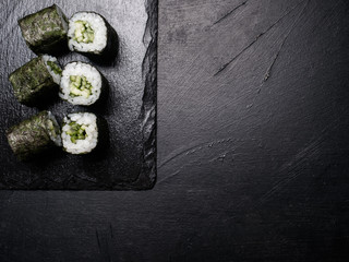 Obraz na płótnie Canvas sushi rolls with salmon covered in nori on dark background. Food photography creative art. Free space concept
