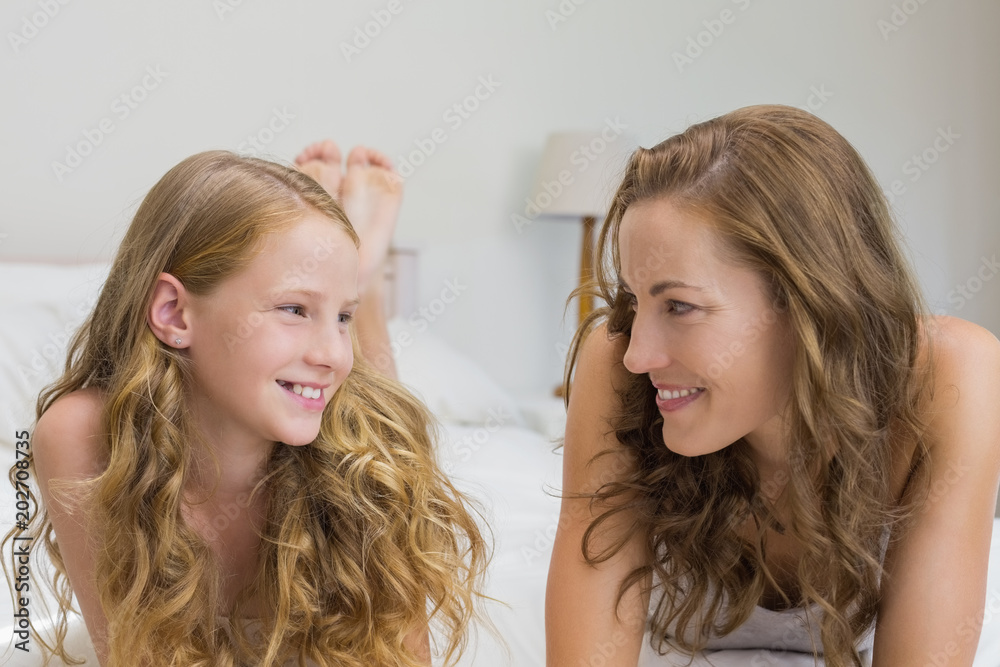 Wall mural Smiling mother and daughter lying in bed