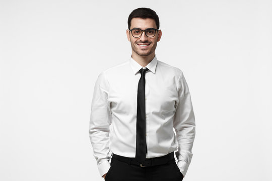 Half-length portrait of young European Caucasian man pictured isolated on grey background dressed in white T-shirt and tie and wearing glasses showing positive smile and readiness to develop