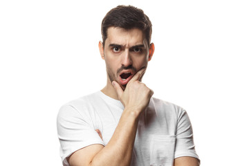 Horizontal portrait of young European Caucasian man pictured isolated on white background looking with eyes wide open with fear or amazement, covering open mouth with palm, astounded with news