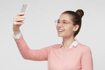 Horizontal photo of young good-looking European Caucasian girl isolated on gray background taking...