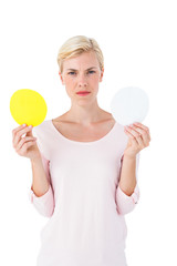 Serious blonde woman holding white and yellow sheets of paper