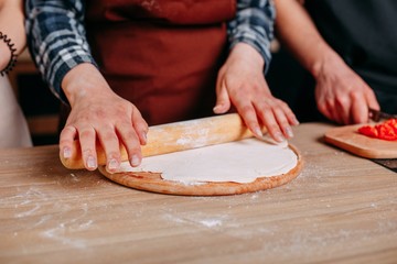 Woman kneading the dough with rolling pin, close up. Food prepar