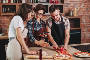 Woman teaching her friends how to cook. Group of people cutting
