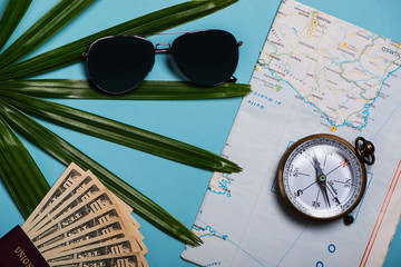 Travel Template Top View. World Map, sunglasses, compass passport, Dollars, palms leaf on blue background