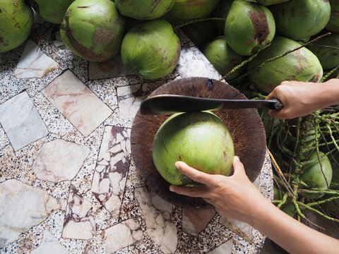 Man Using Knife To Chopped Fresh Coconut For Drink And Green Coconuts Background, Top View.