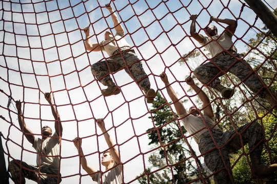 Military soldiers climbing rope during obstacle course - Powered by Adobe