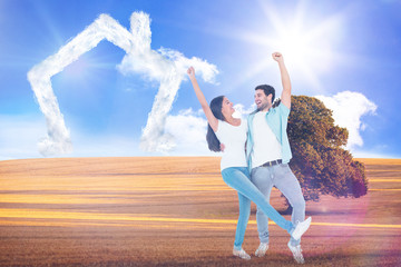 Fototapeta na wymiar Happy casual couple cheering together against sunny brown landscape
