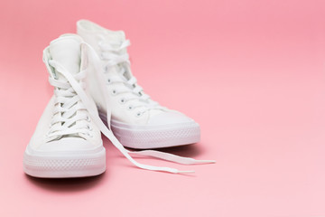 Pair of new white sneakers on pink background