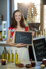 Female shop assistant holding open sign board