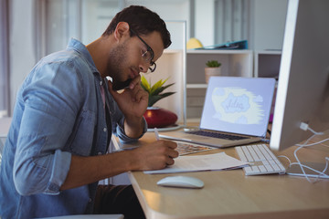 Businessman talking on phone while working at creative office