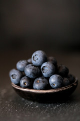 Blueberry .Moody Food Photography. ripe blueberries in a  black clay cup on a black background. Dark Key. The harvest of blueberries. 