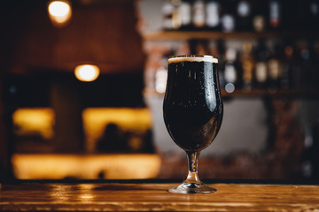 Glass glass with cold unfiltered beer on background of bar.