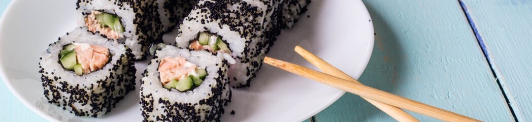 Banner of Maki Sushi - Roll made of Cream Cheese, Tamago, Cucumber and Smoked Eel inside. Black Tobiko outside