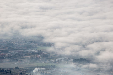 Fototapeta na wymiar Beautiful aerial view of Umbria valley in a winter morning, with fog covering trees and houses