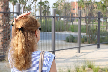 A view of the woman from behind. A woman touches her hair.