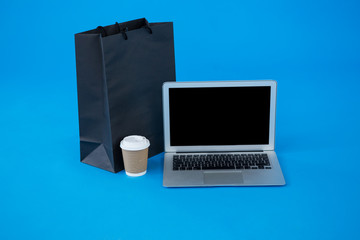 Shopping bag and disposable coffee cup with laptop