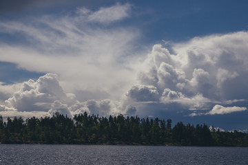 A blue sky with clouds over a forest and a lake