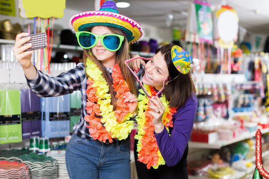 Happy women friends making funny photo in carnival outfits shop