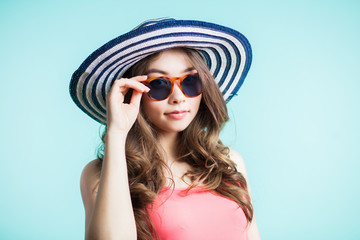 Young beautiful woman in bikini, hat and sunglasses standing on the beach. summer holidays and vacation concept.