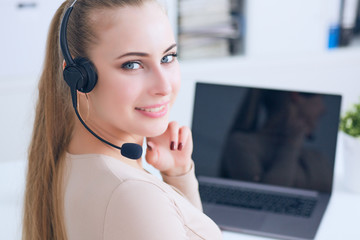 Portrait of happy smiling female customer support phone operator at workplace.